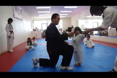 Маленький боец тхэквондо получает белый пояс